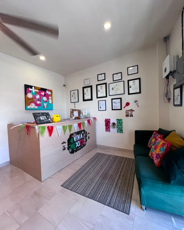 Recepción con escritorio, sofá verde y cuadros en la pared.
